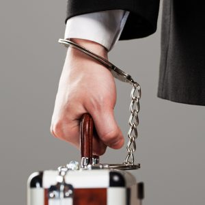 Case attached to businessman's hand with metal handcuffs